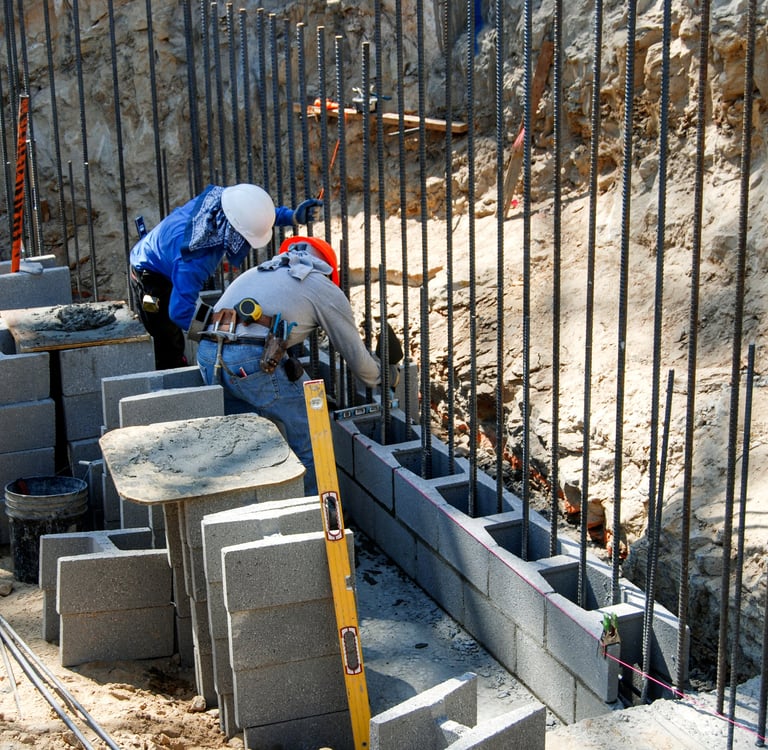 Concrete retaining wall installation with reinforced block construction
