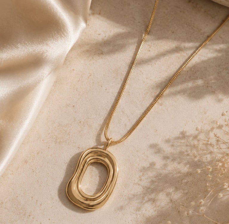 Gold pendant necklace displayed on a neutral surface with soft natural light.