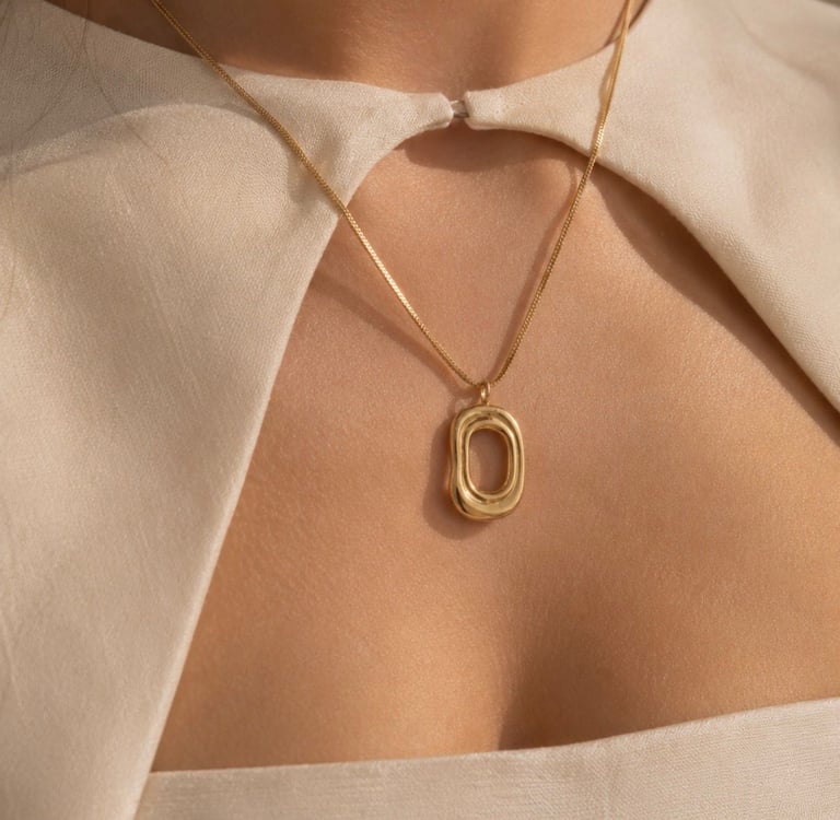 Gold pendant necklace styled with a cream off-shoulder top in warm natural light.