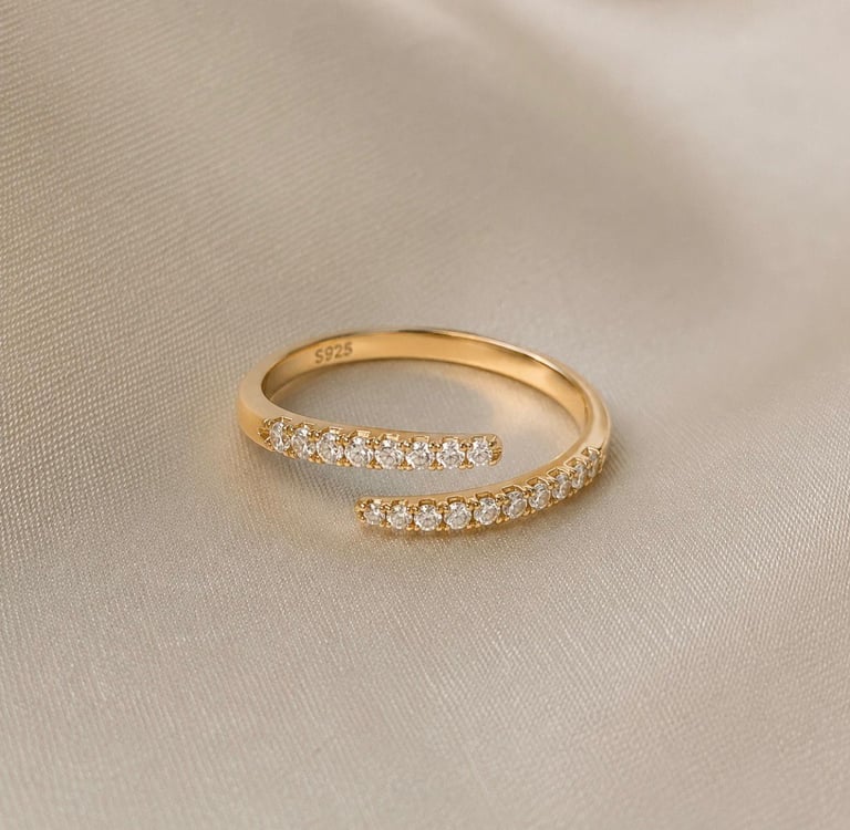 Minimalist gold crystal open ring displayed on a soft cream fabric background.