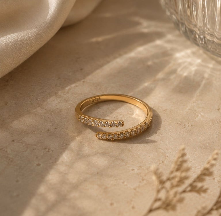 Gold crystal open ring with sparkling stones styled on a neutral stone surface.