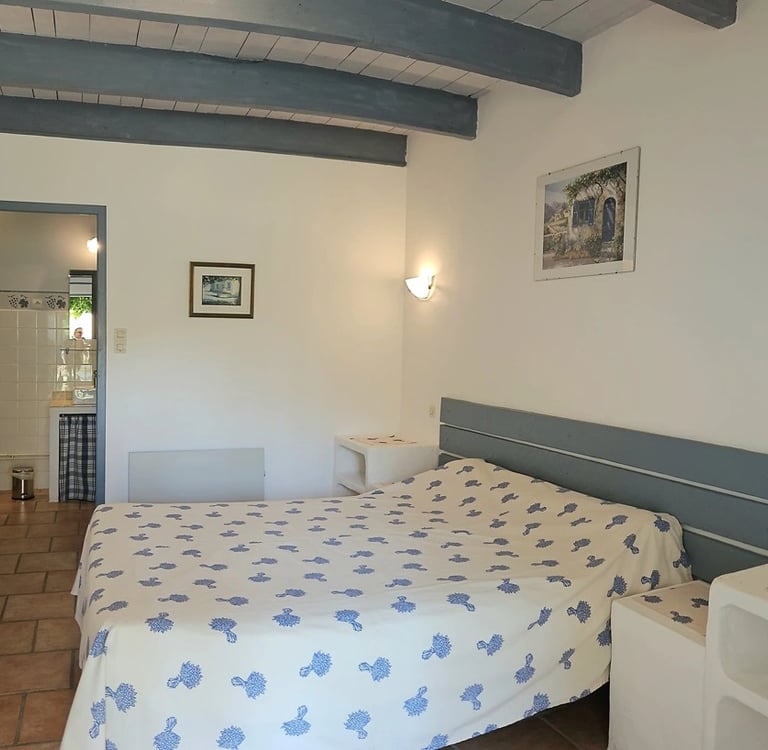 chambre romarin "la ramade" avec un grand lit et un petit lit, mur blanc, poutre et placard bleu 