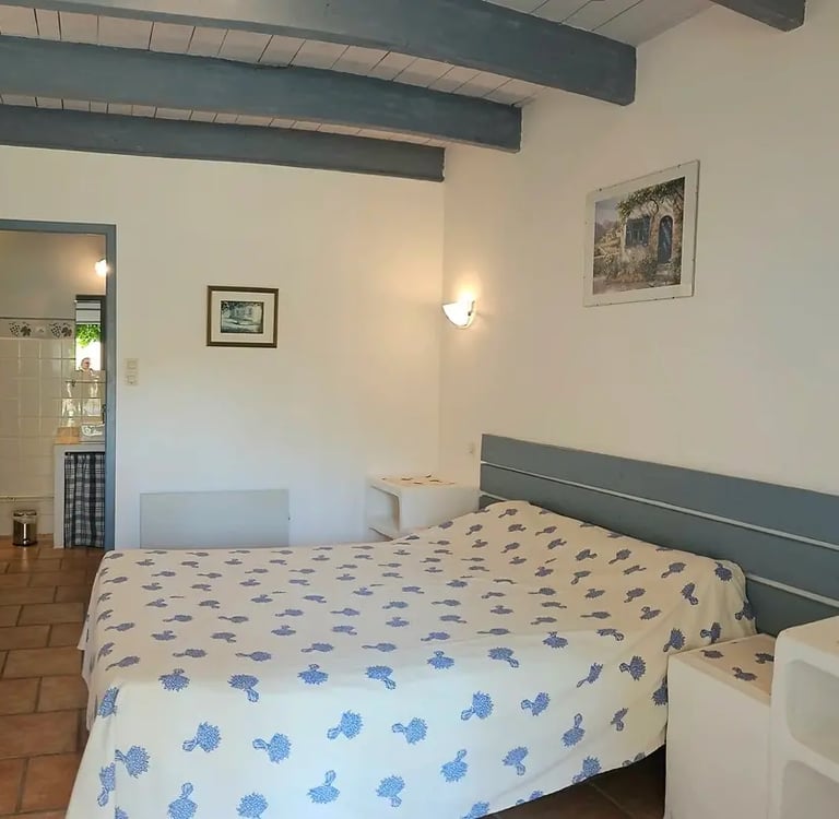 chambre romarin "la ramade" avec un grand lit et un petit lit, mur blanc, poutre et placard bleu 