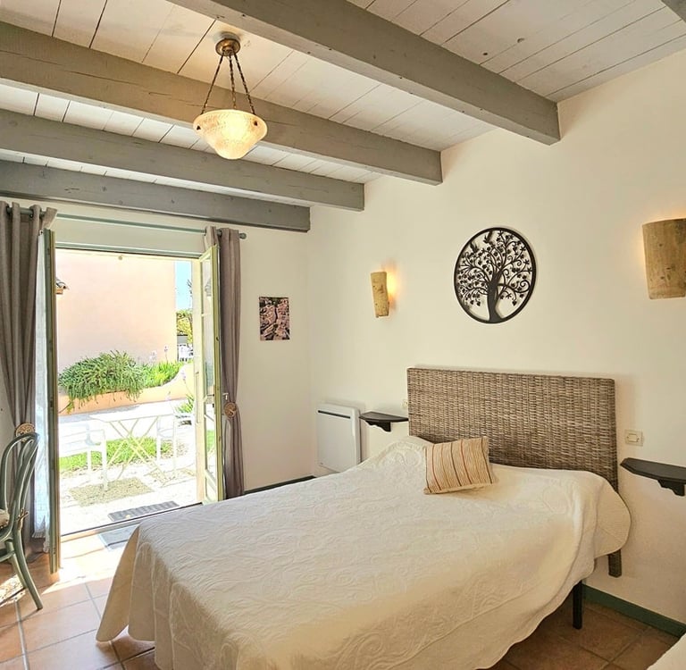 Chambre sauge de la maison d'hôtes la ramade, grand lit vue porte fenêtre extérieur.