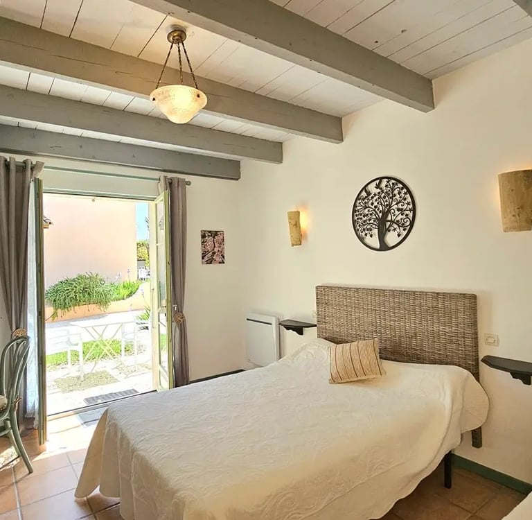 Chambre sauge de la maison d'hôtes la ramade, grand lit vue porte fenêtre extérieur.