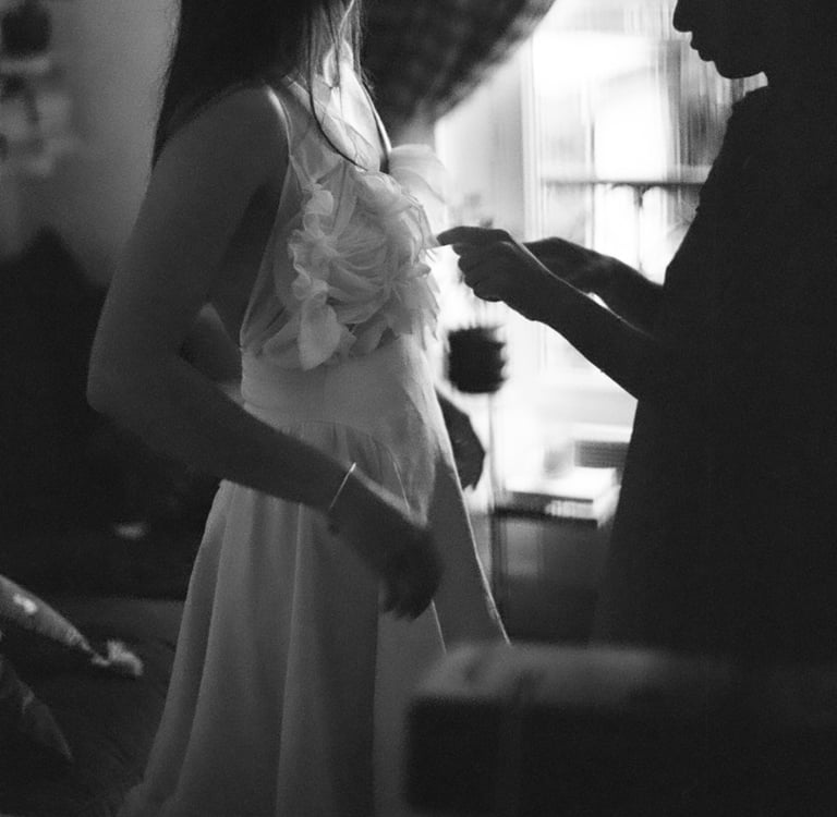 Mains d'une couturière ajustant le corsage d'une robe de mariée couture en lumière naturelle