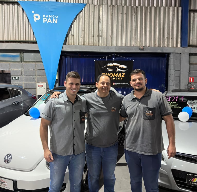 two men standing next to each other in front of a car