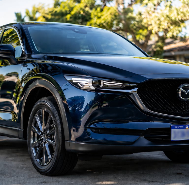 A sleek navy blue Mazda CX-5 SUV parked on a sunny residential driveway after paint correction 