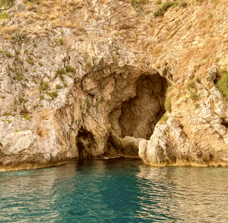 a boat is coming out of a cave in the mountains