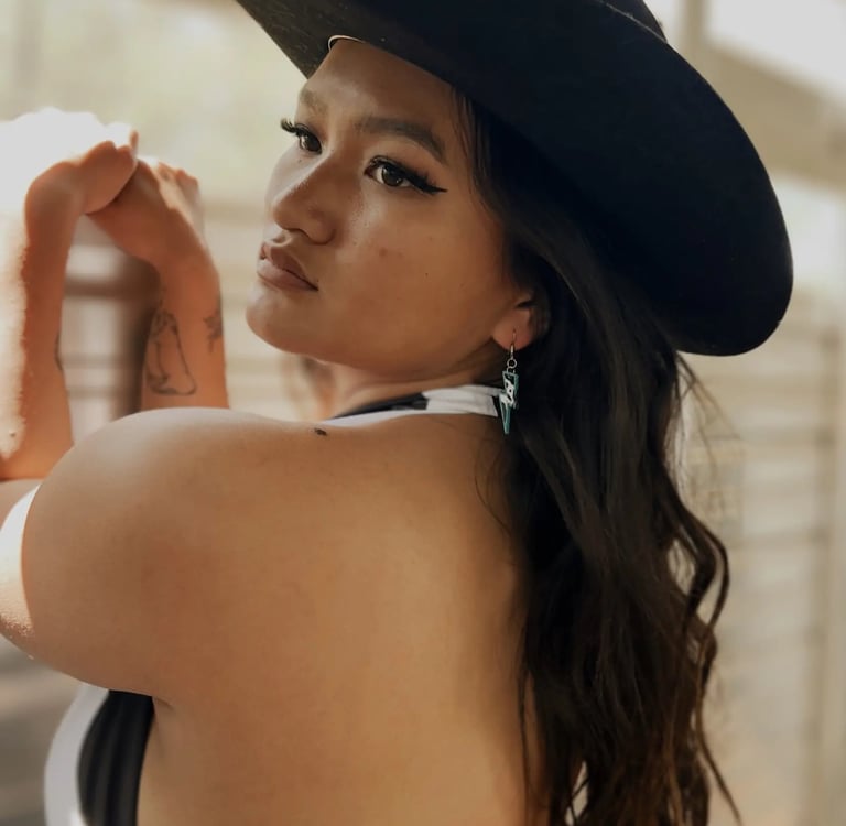 Amelia posing in a horse trailer with a black cowboy hat on