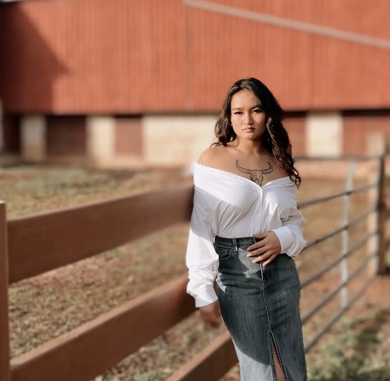 Woman in a white top posing against a fence