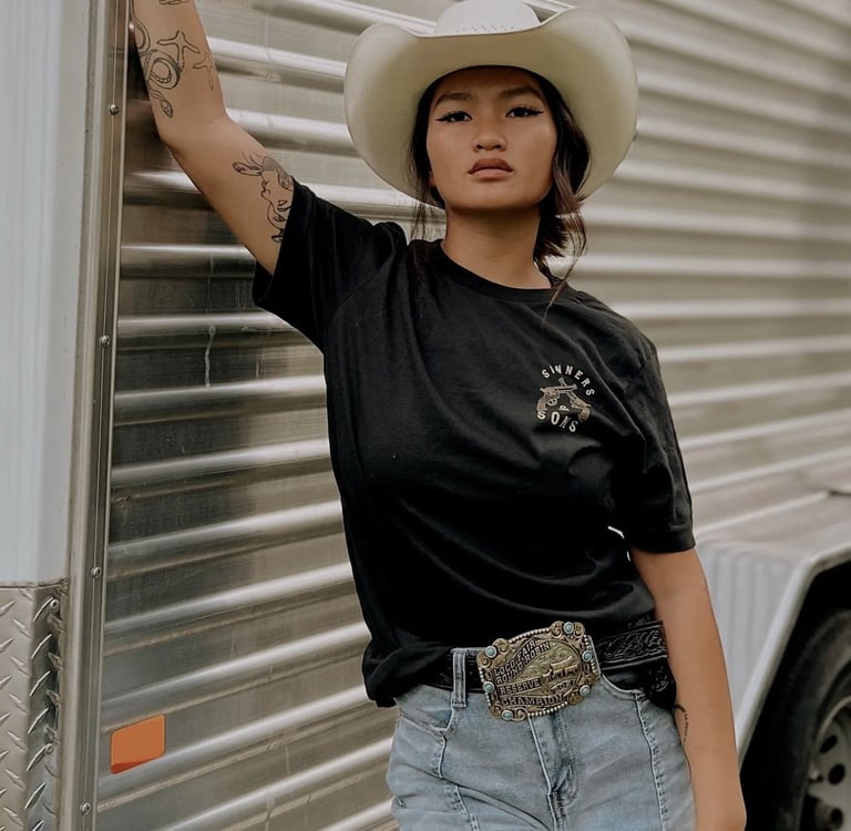 Woman in a black top and cowboy hat next to a horse trailer