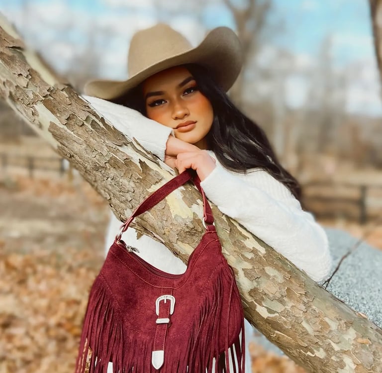 a woman in a white dress and hat with a red fringe purse