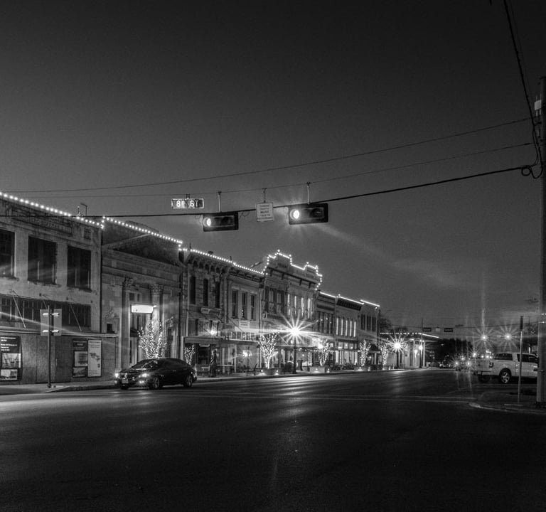 Night photo of Austin Ave in Georgetown, Texas, with it's historic buildings illuminated by streetlights 