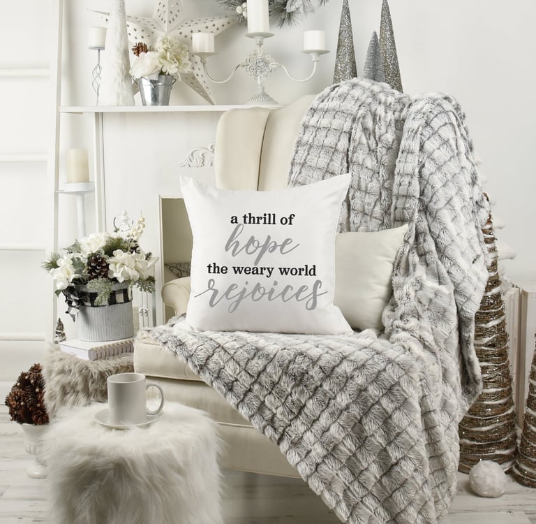 Cozy Christmas home with wing chair & fur throw. Coffee mug. Pillow reads "a thrill of hope the weary world rejoices."