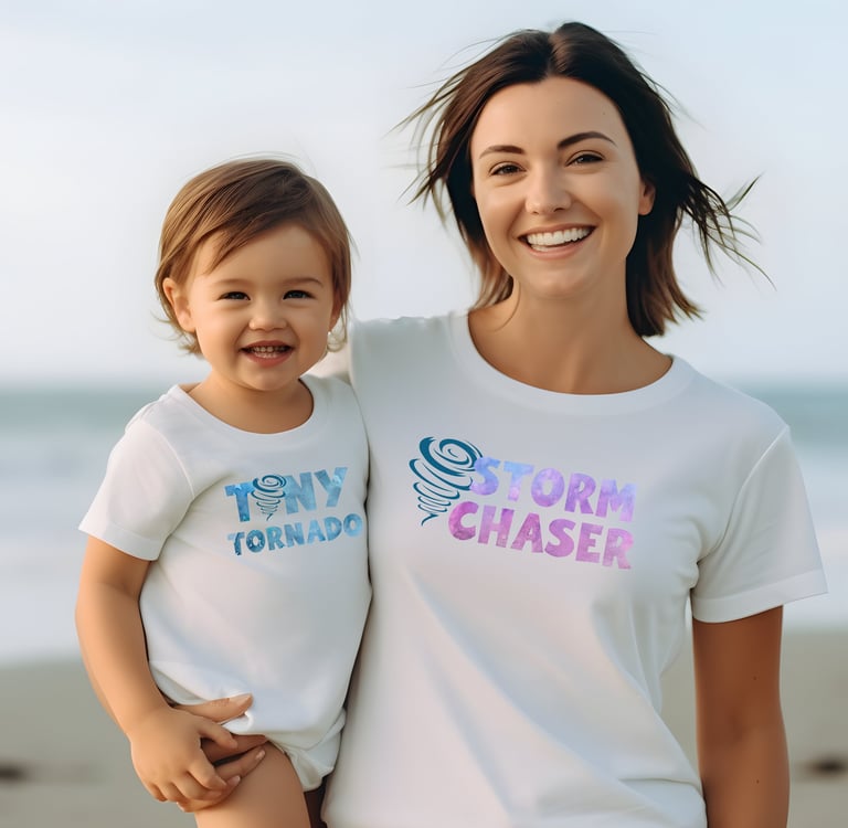 A toddler and his mother in matching shirts. His reads "Tiny Tornado" and hers "Storm Chaser."