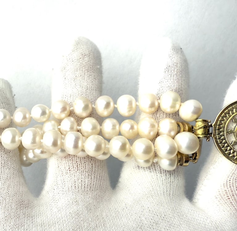 a woman's hand holding a bracelet with a gold coin