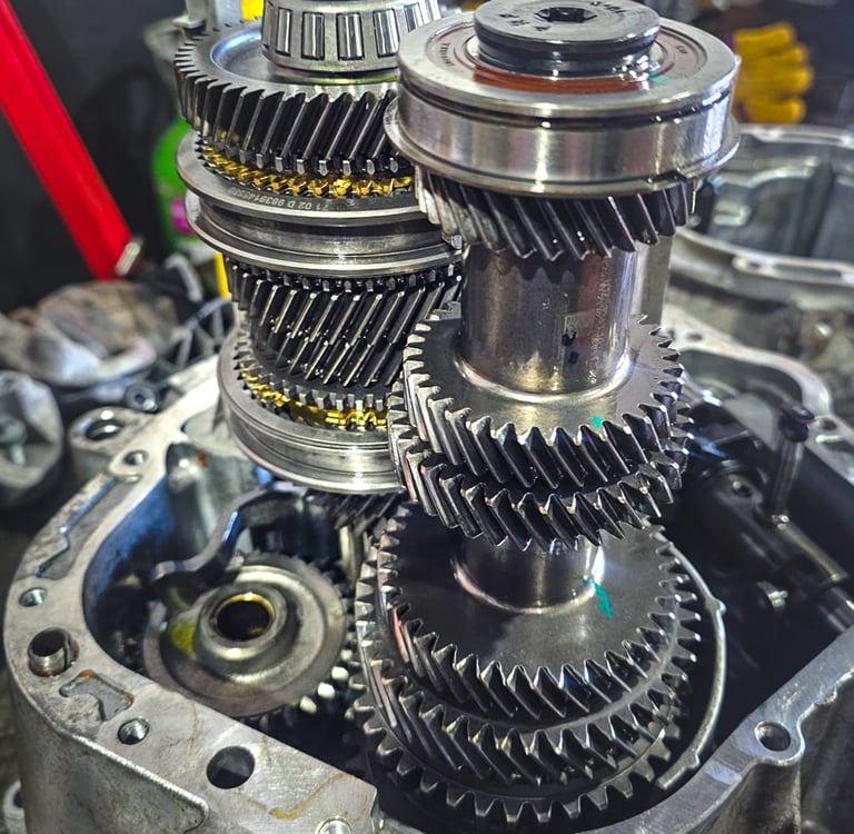 Internal view of a manual car transmission showing metal gears and shafts during a gearbox repair.