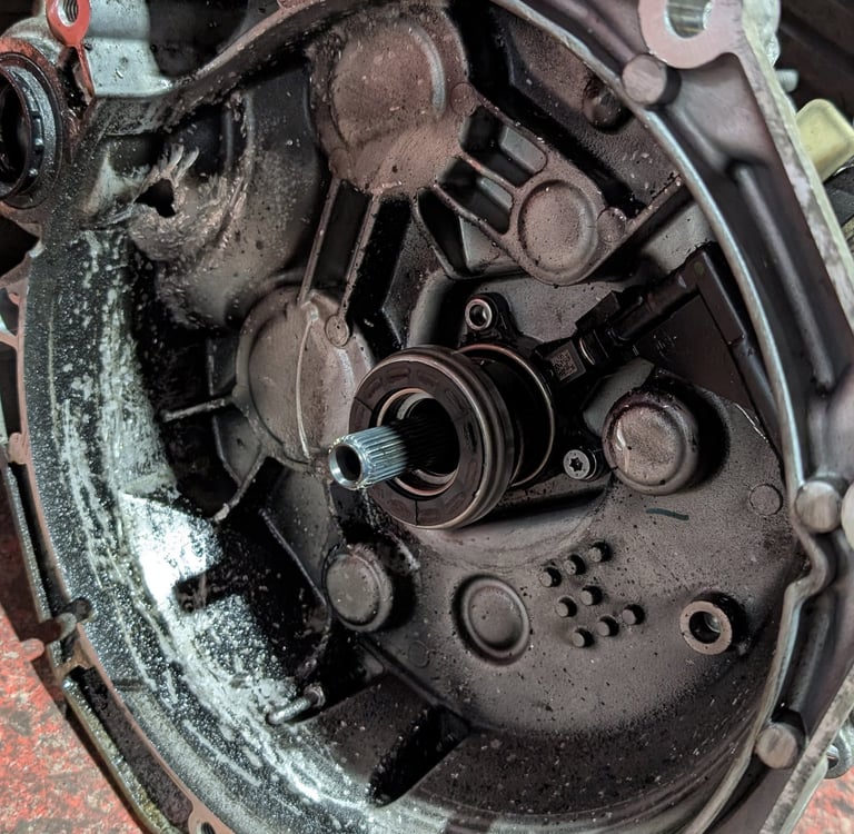 A grease-covered automotive transmission bell housing with an input shaft and release bearing.