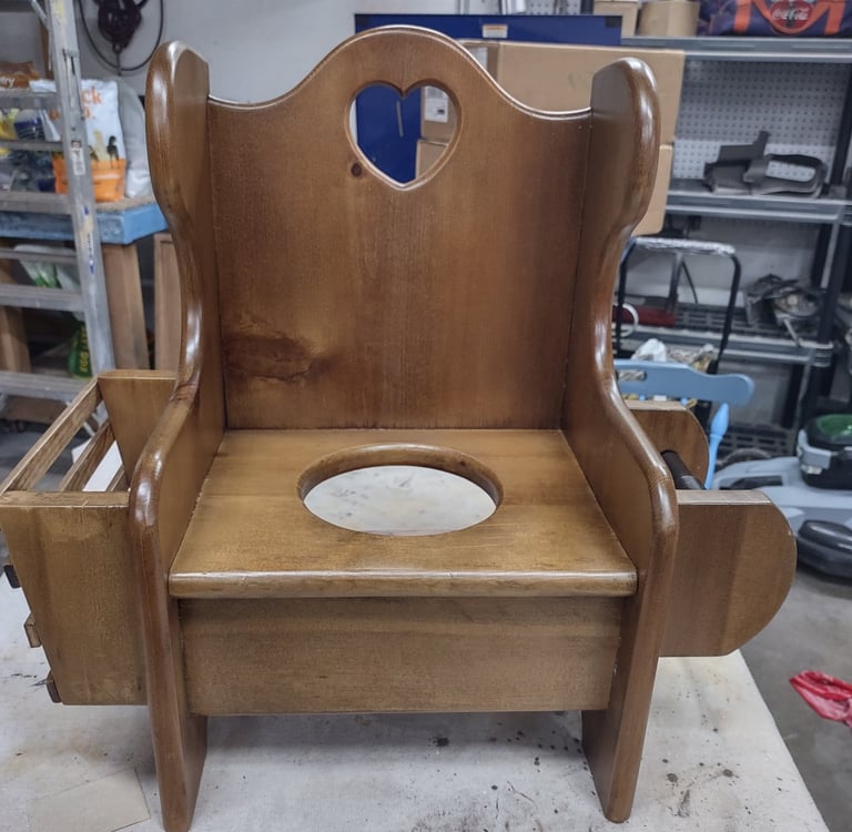  Restored antique wooden potty chair for toddlers featuring a heart cutout and side storage.