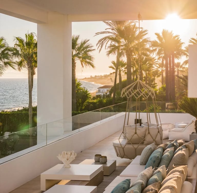 Covered terrace seating area overlooking the coastline at sunset
