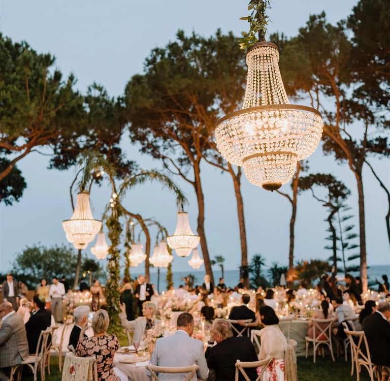 Elegant outdoor dinner at Villa El Rincon with chandeliers and guests under the trees