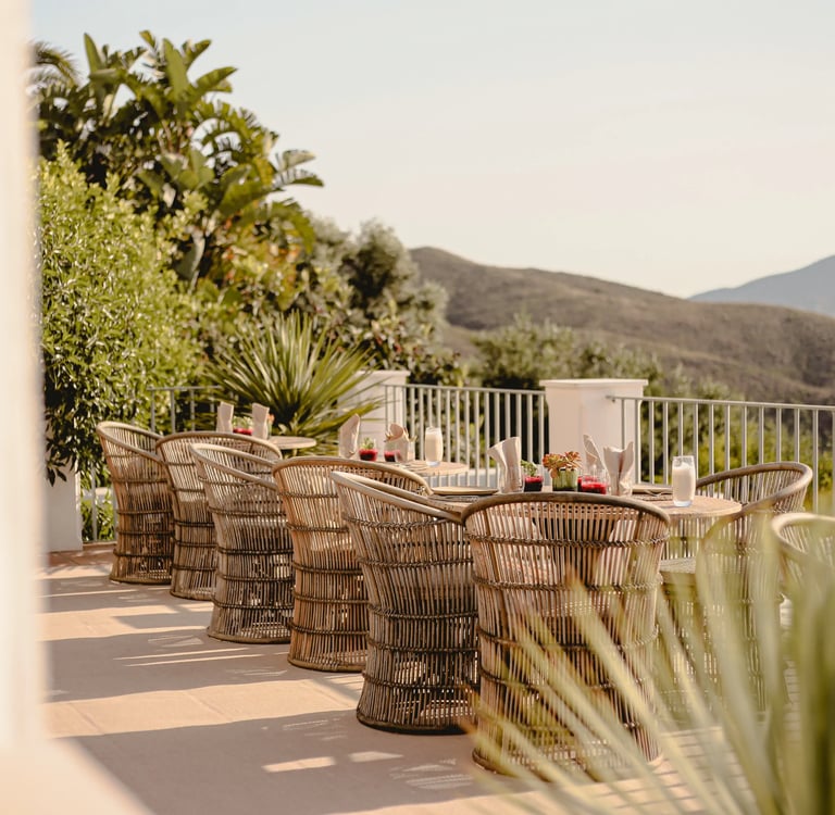 Terrace dining setup with woven chairs and valley views