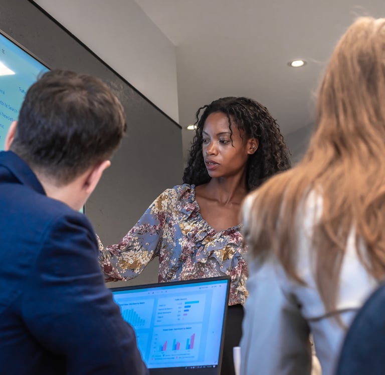 Woman presenting data on a screen to colleagues during a meeting.