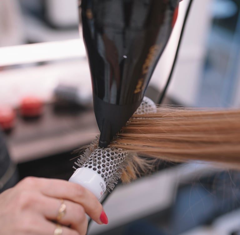a woman is blow drying her hair in a salon