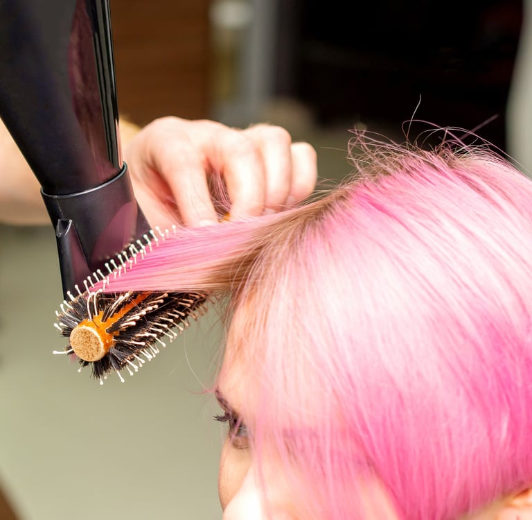 Hair model with vibrant pink full-head color during blow-dry.