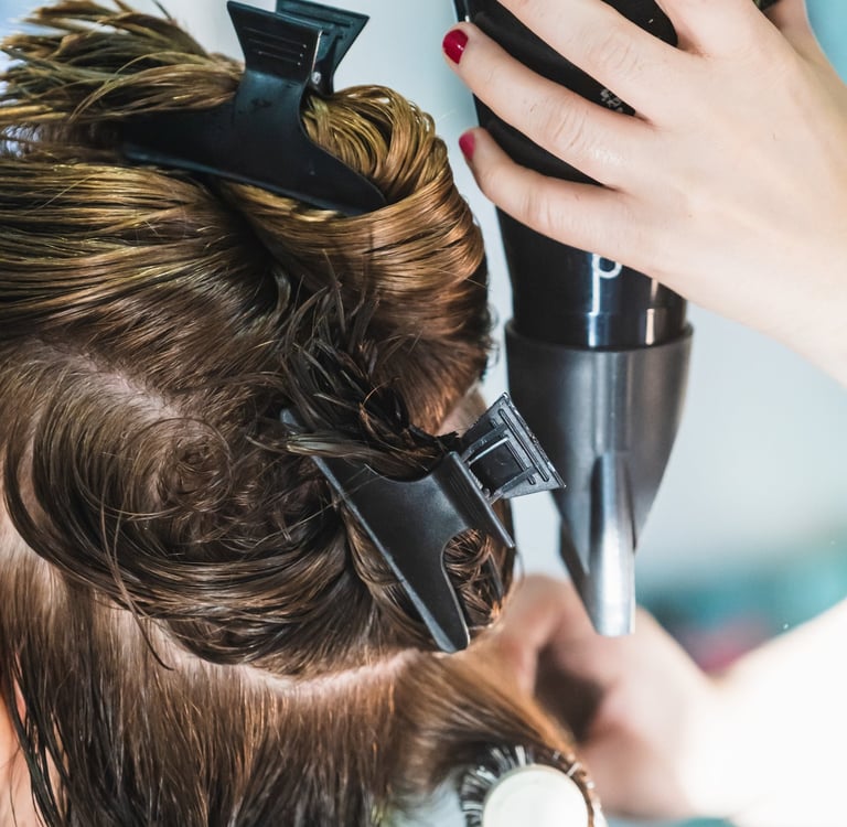 a woman is blow drying her hair in a salon