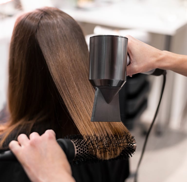 a woman is blow drying her hair in a salon