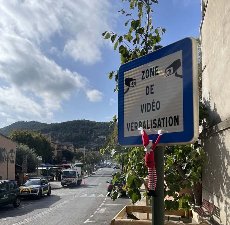photo d’un lutin farceur accroché à un panneau en ville, tradition de Noël