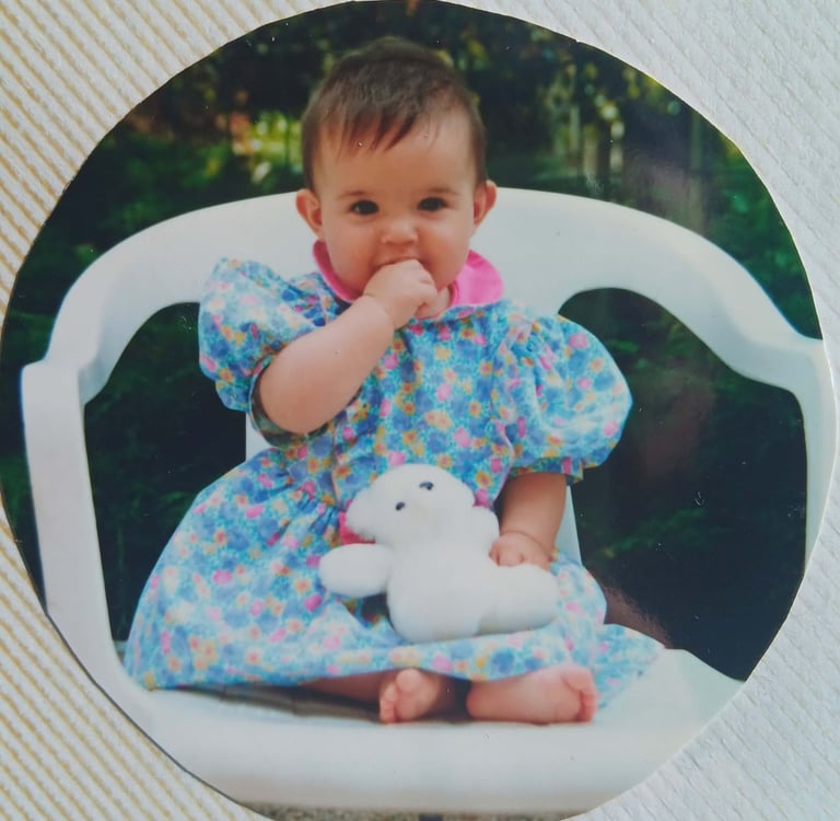 Natacha bébé tenant sa peluche blanche contre elle