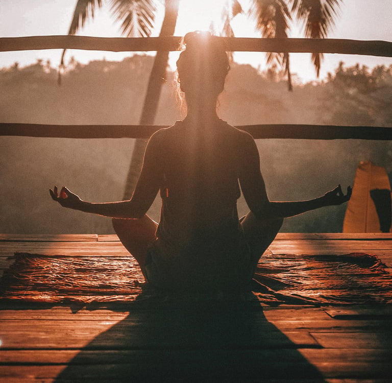 Woman meditating at sunrise in tropical setting, practicing mindfulness, calm, and inner peace.