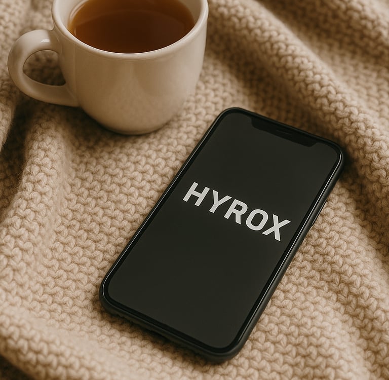 A cozy blanket, a steaming cup of tea, and a phone with message "HYROX" on the screen