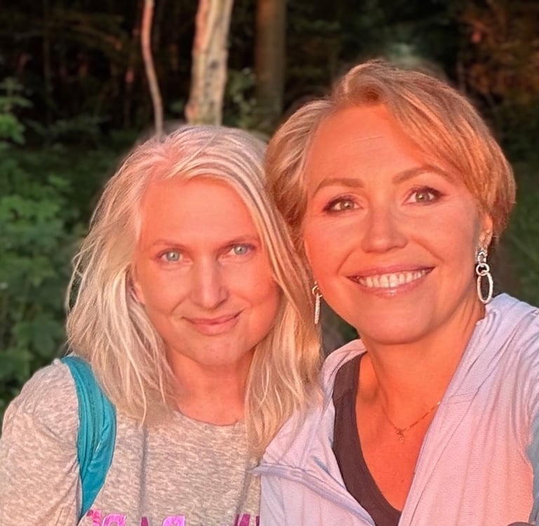 Two smiling women in nature at sunset, glowing with warmth, friendship, and joyful connection.