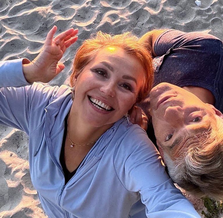 Smiling couple enjoying sunset on the beach, radiating joy, love, and playful connection.