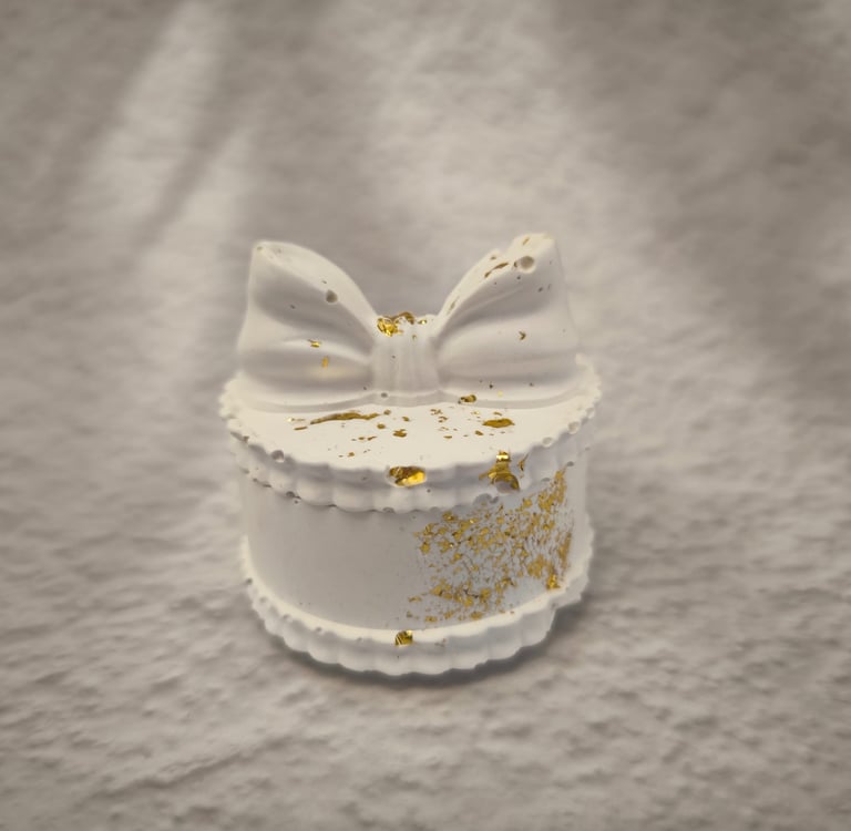 Balta papuošalų dėžutė su kaspino formos dangteliu ir auksinėmis detalėmis