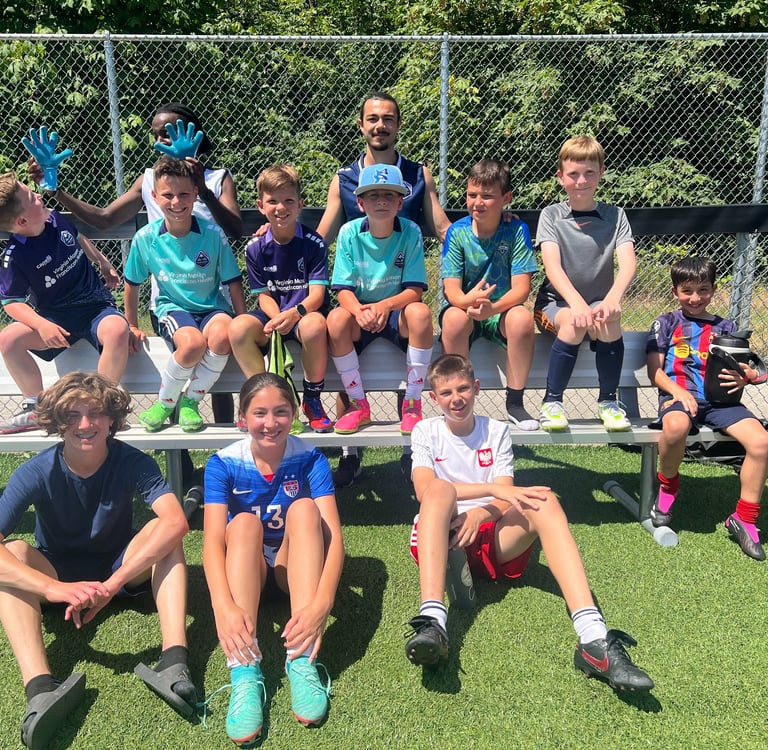 Kids from soccer camp sitting on a bench.