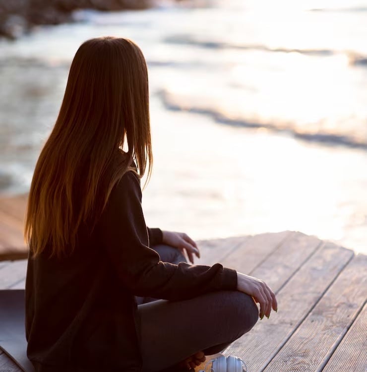 Personne assise face à la mer, dans un moment de calme et d’introspection, gestion des émotions