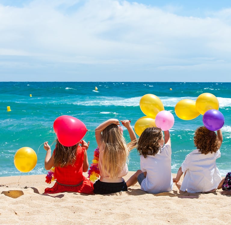 Children sitting on beach with color balloons
