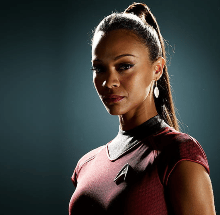 two men standing on a roof top with a city in the background