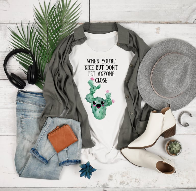 Plant-themed graphic tees and cozy hoodies displayed flatlay with jeans, boots, and greenery — Miss Chatty Plants apparel.
