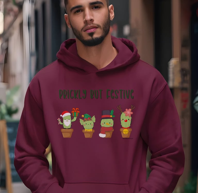 Man wearing maroon hoodie with “Prickly but Festive” cactus design — Christmas hoodie for plant lovers by Miss Chatty Plants