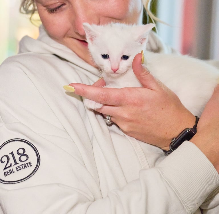 a woman holding a white kitten in her arms