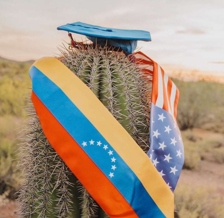 A saguaro cactus wearing a blue graduation cap with Venezuelan and American flag stoles in the desert.