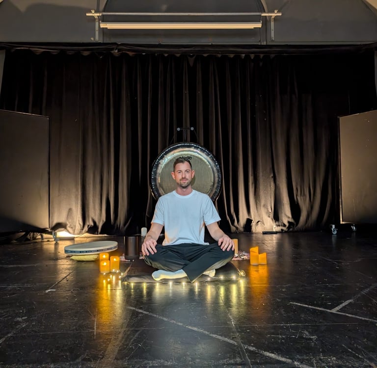 a man sitting in front of a gong leading a relaxing sound bath