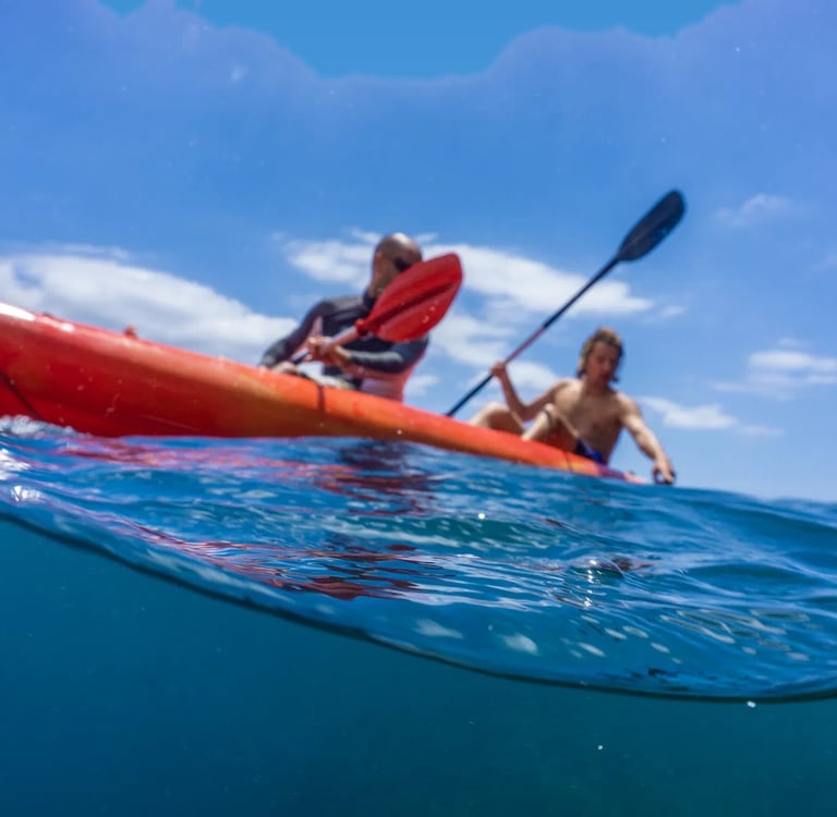 Two people on a red kayak on the open Atlantic Ocean near the coast of Funchal, Madeira