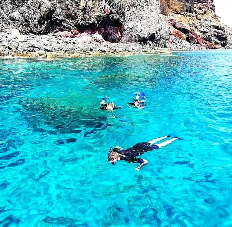 roup snorkeling in crystal clear turquoise water along the rocky volcanic coastline of Ponta de São Lourenço, Madeira